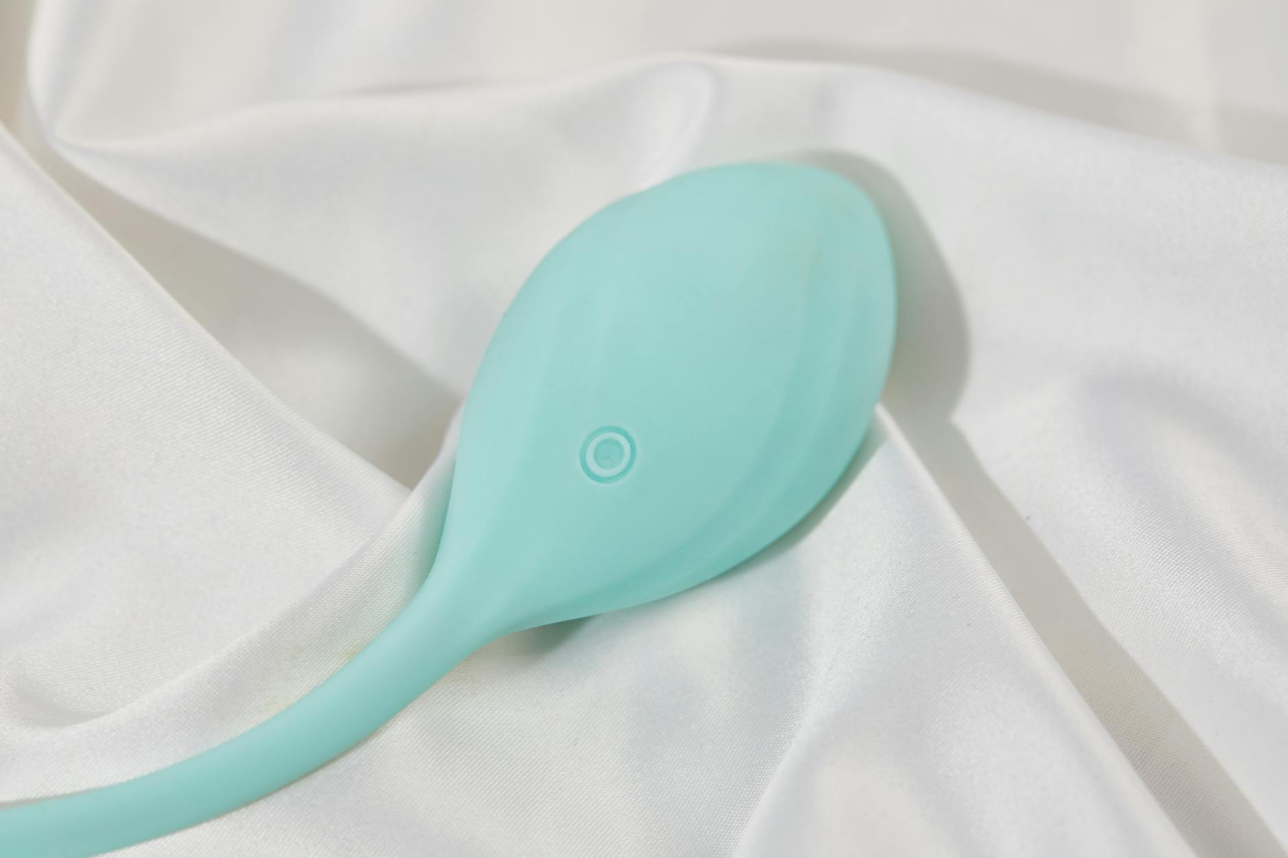 Woman thoughtfully holding blue and pink silicone vibrators while considering her options