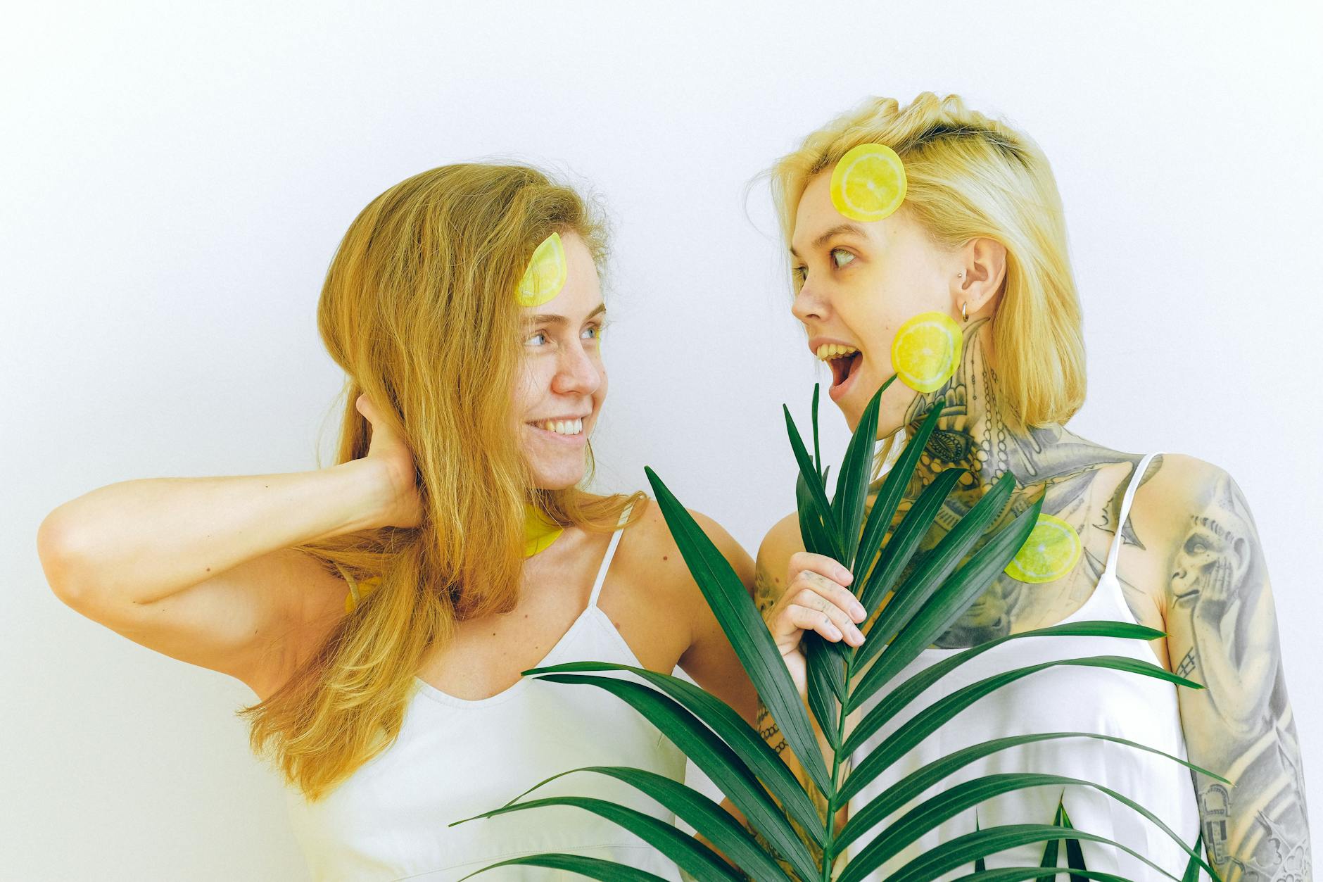 Two people smiling and holding fresh lemons indoors, expressing joy and playfulness.