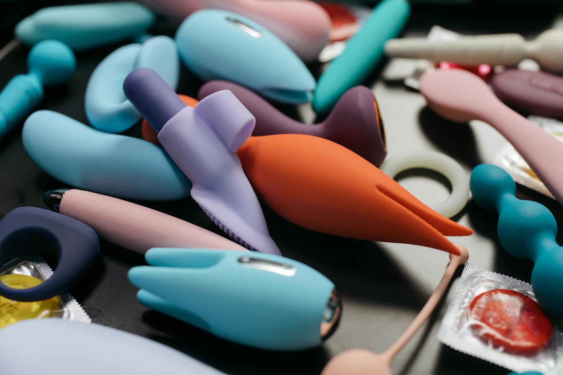 Woman holding blue and pink silicone vibrators in contemplative pose
