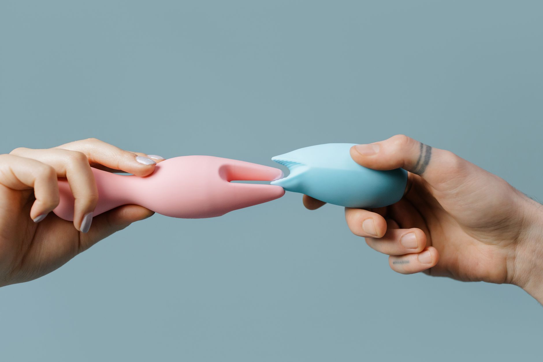 Hands holding pastel silicone adult toys, representing openness and communication in partnerships