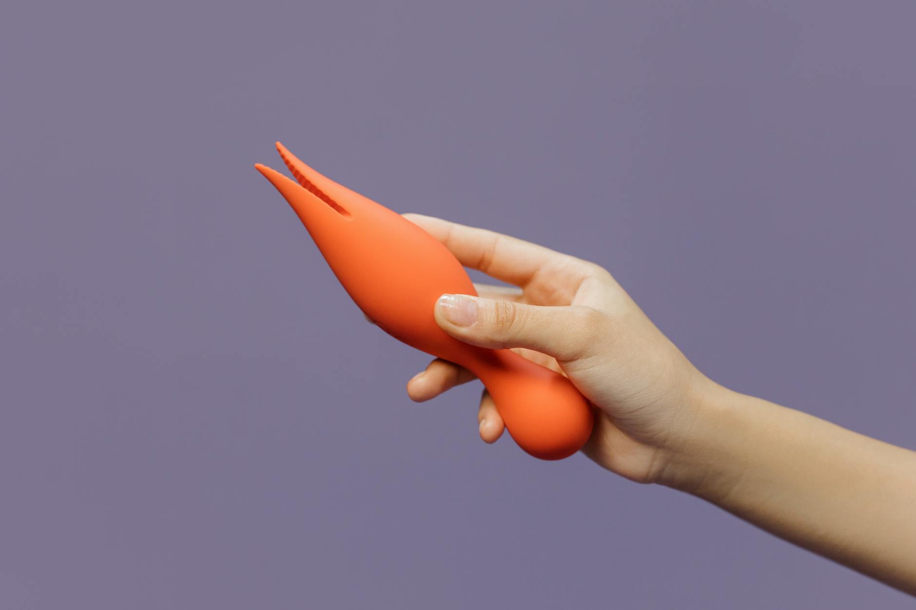 Close-up of hands holding a vibrant lemon vibrator against a minimalistic purple backdrop