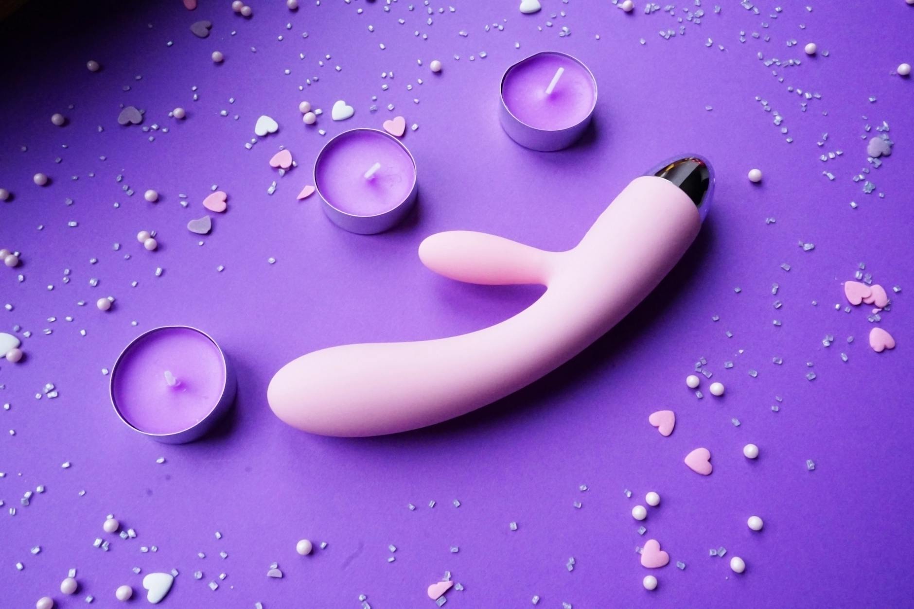 A person holding a basket containing colorful vibrators and a pink flower.